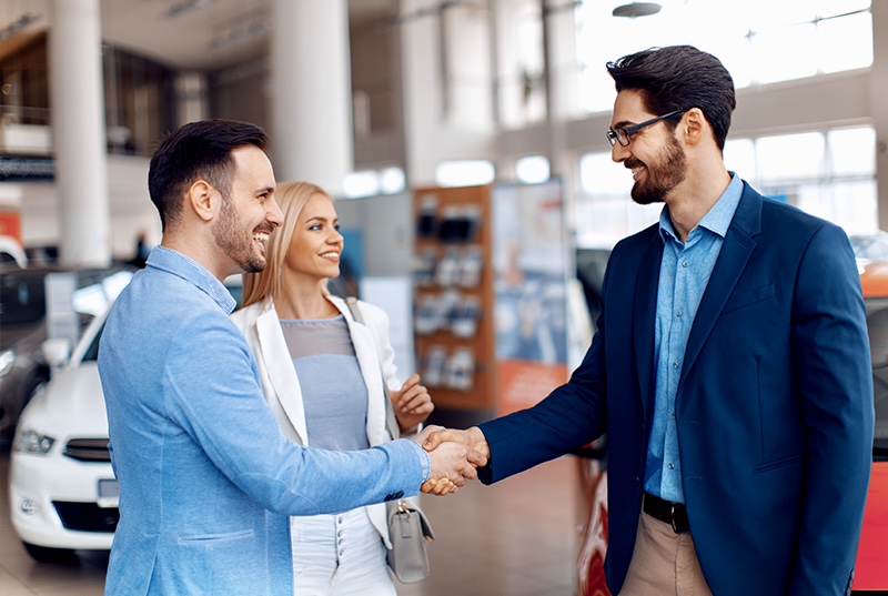 Drive Select Finance broker shaking hands with a couple at a car dealership