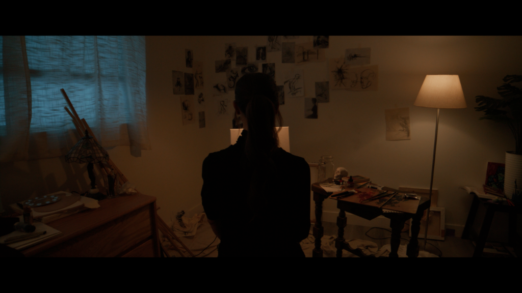 Palette of Dreams still of a character standing in a dim studio space