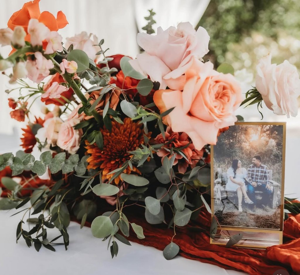Lush floral centerpiece with roses and couple portrait
