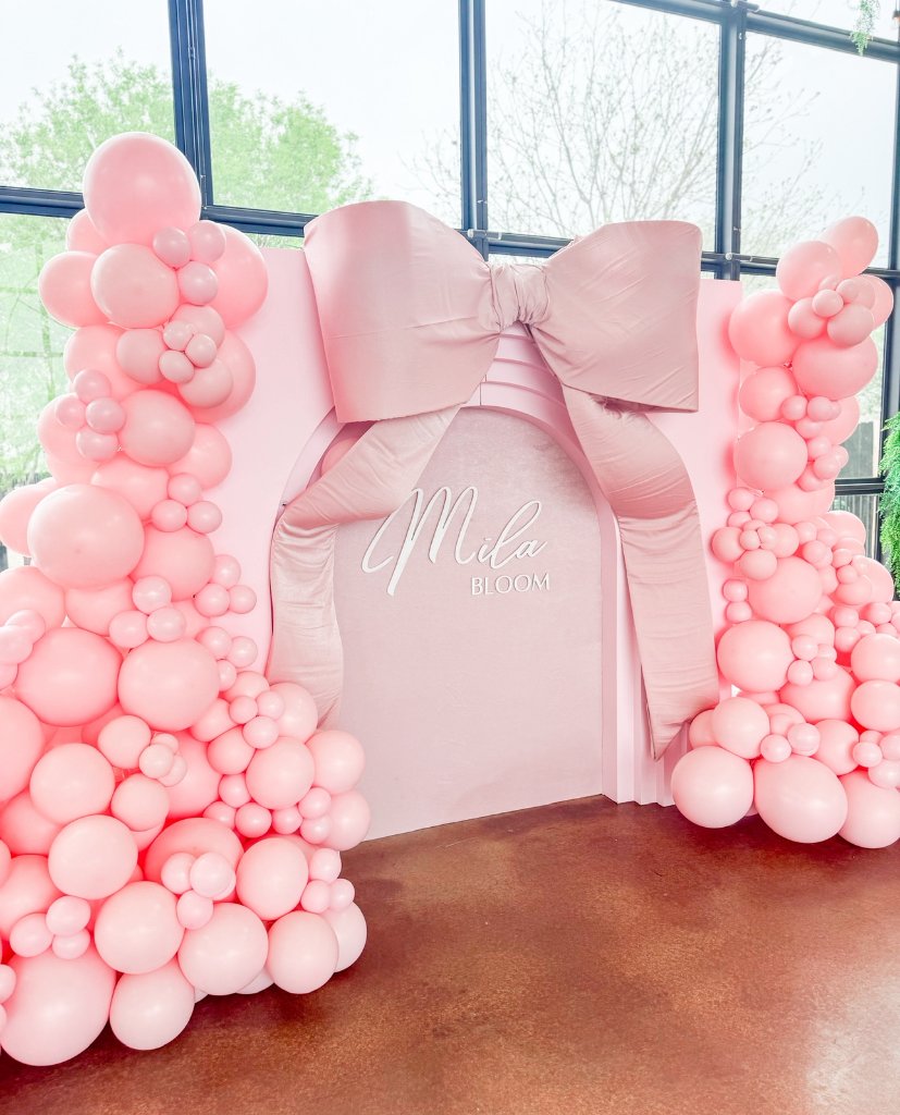 Pink baby shower balloon wall and bow backdrop