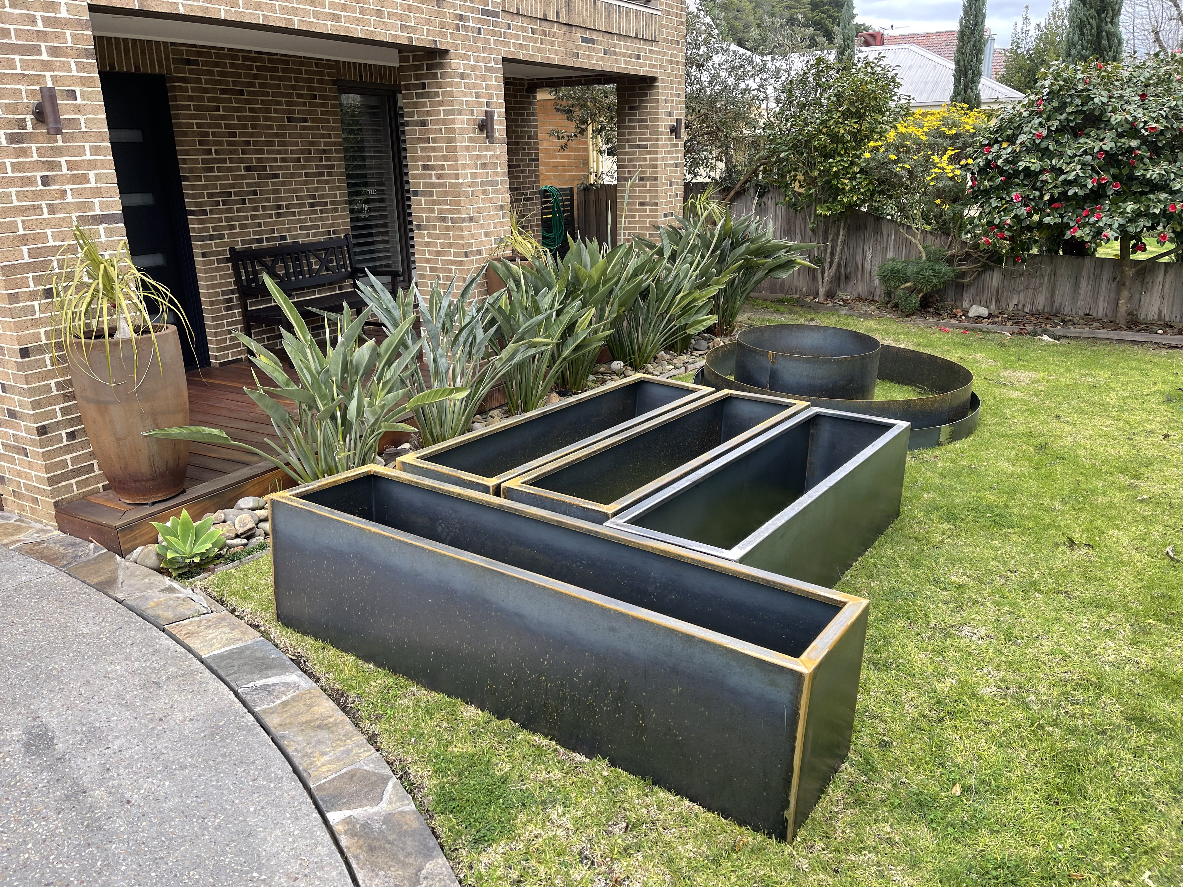 Corten planter boxes arranged on a residential lawn with garden ring
