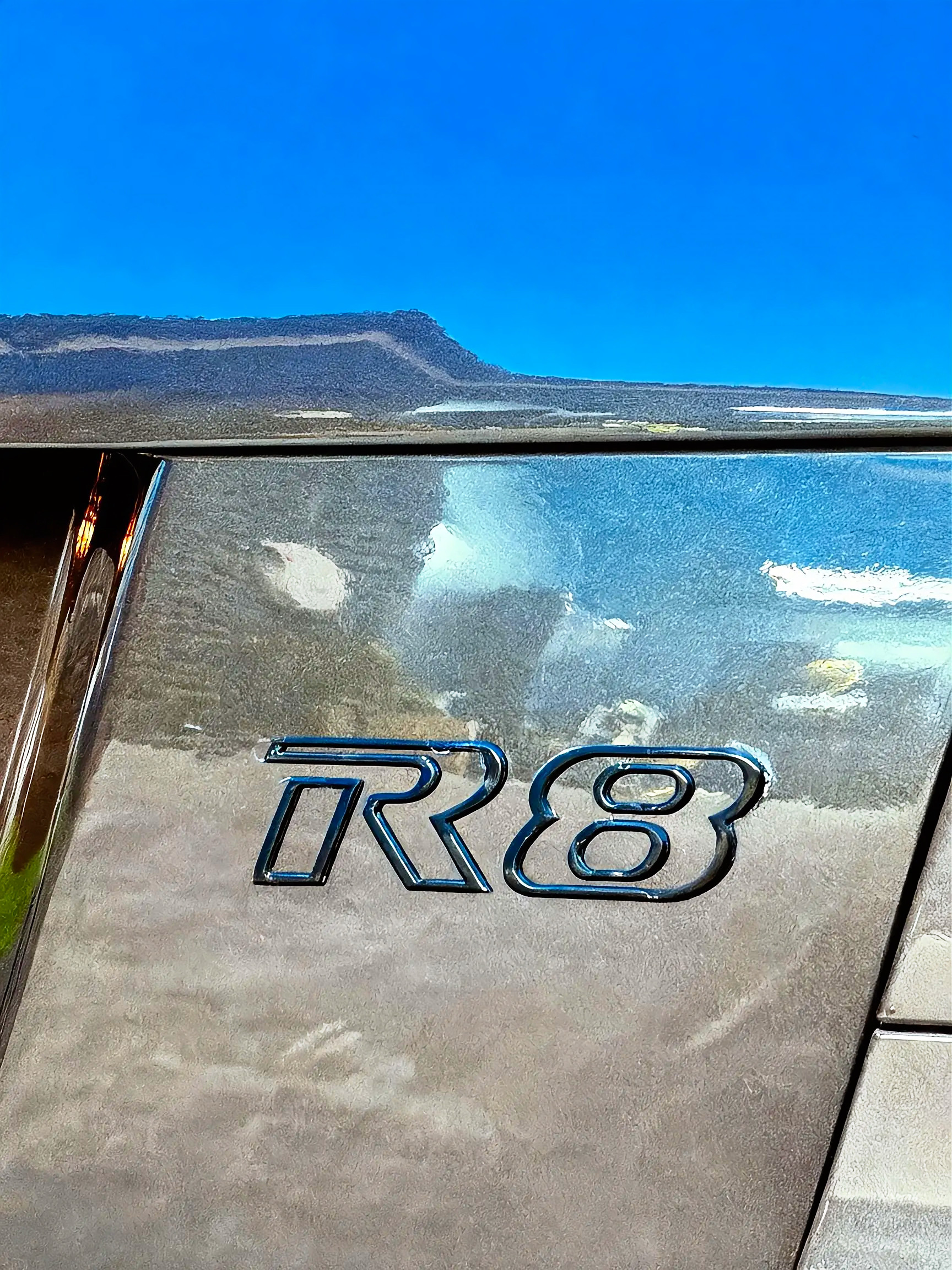 R8 badging, with the sky reading clean through the finish.
