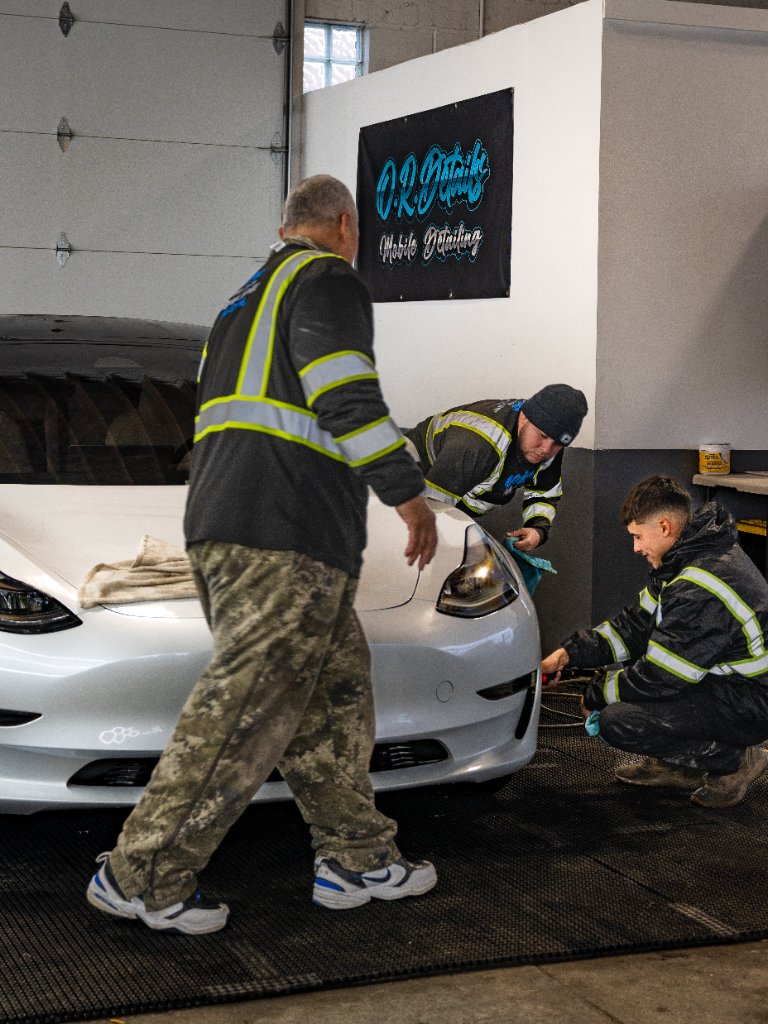 Three techs working the Tesla in the shop