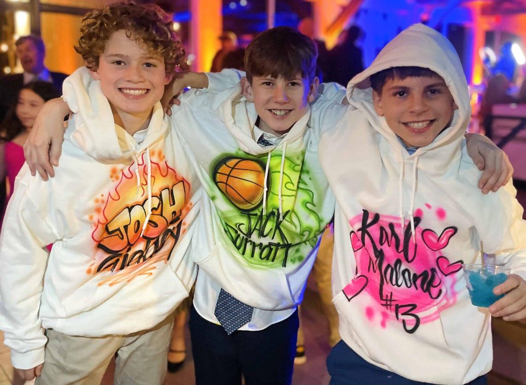 Kids showing off custom airbrush hoodies at a Bar Mitzvah party