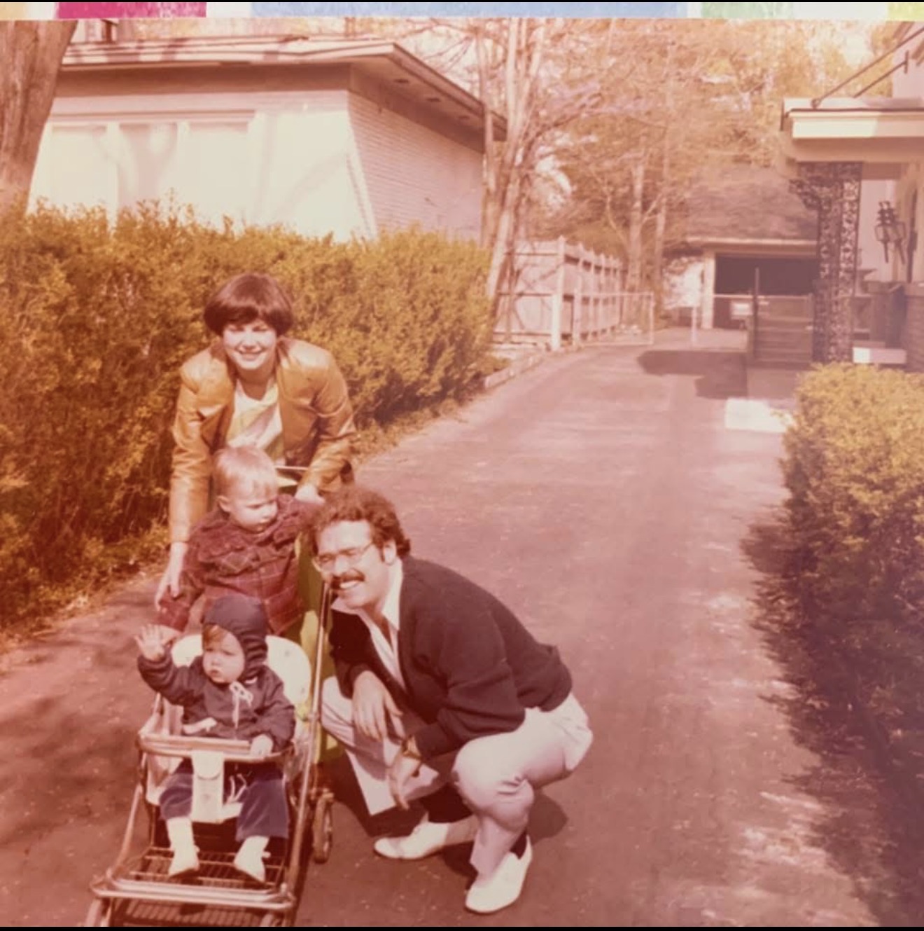 Parents with two small children and a stroller on a driveway