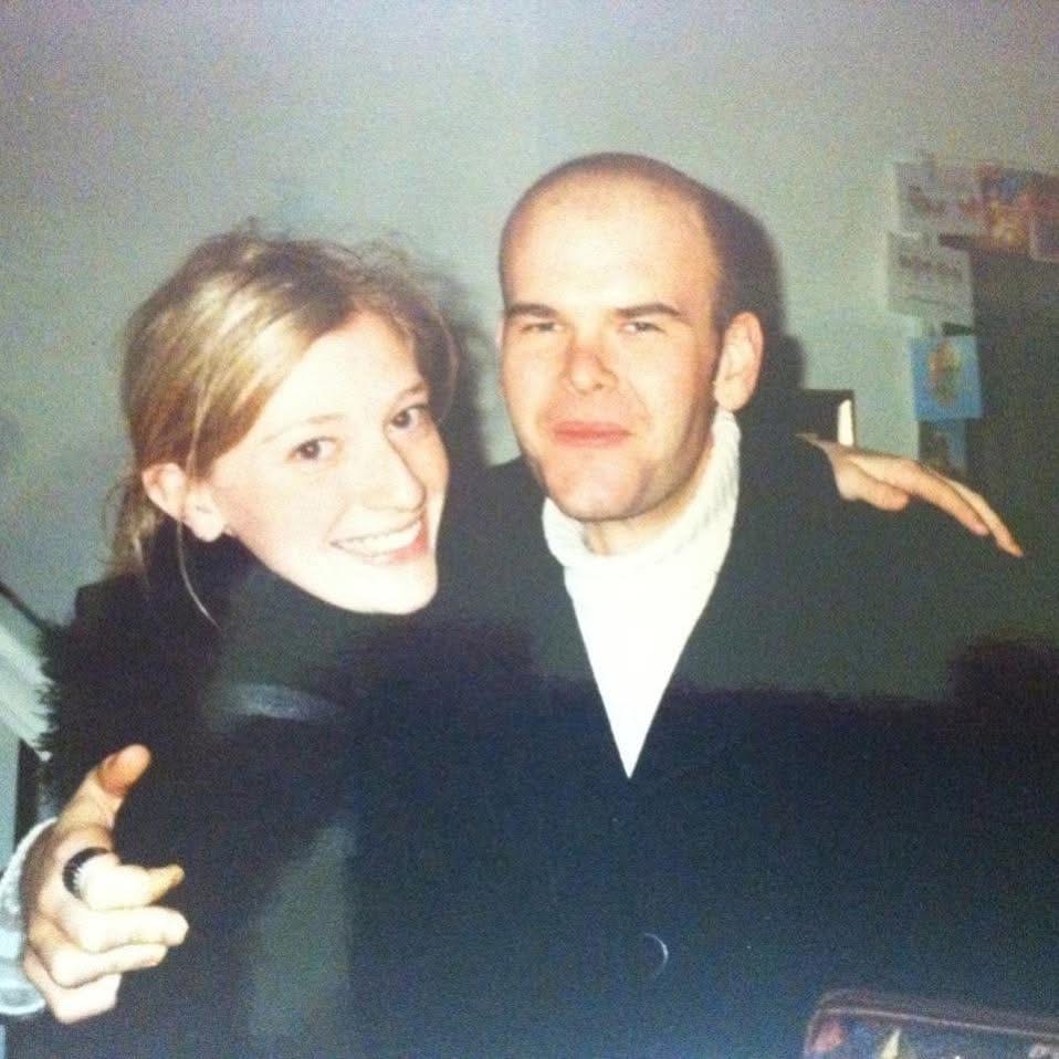 A young couple, arms around each other, smiling at the camera
