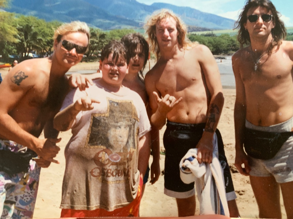 Five friends on a beach in Maui, throwing horns at the camera
