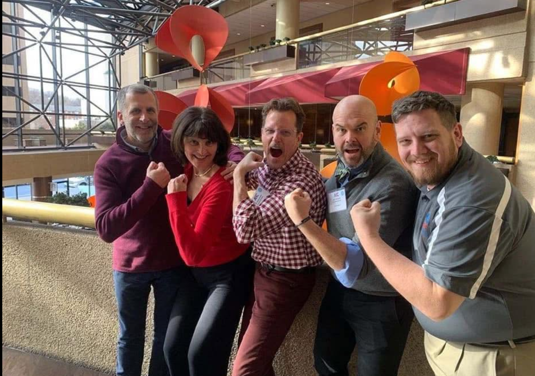Five service commission colleagues flexing and laughing at a conference
