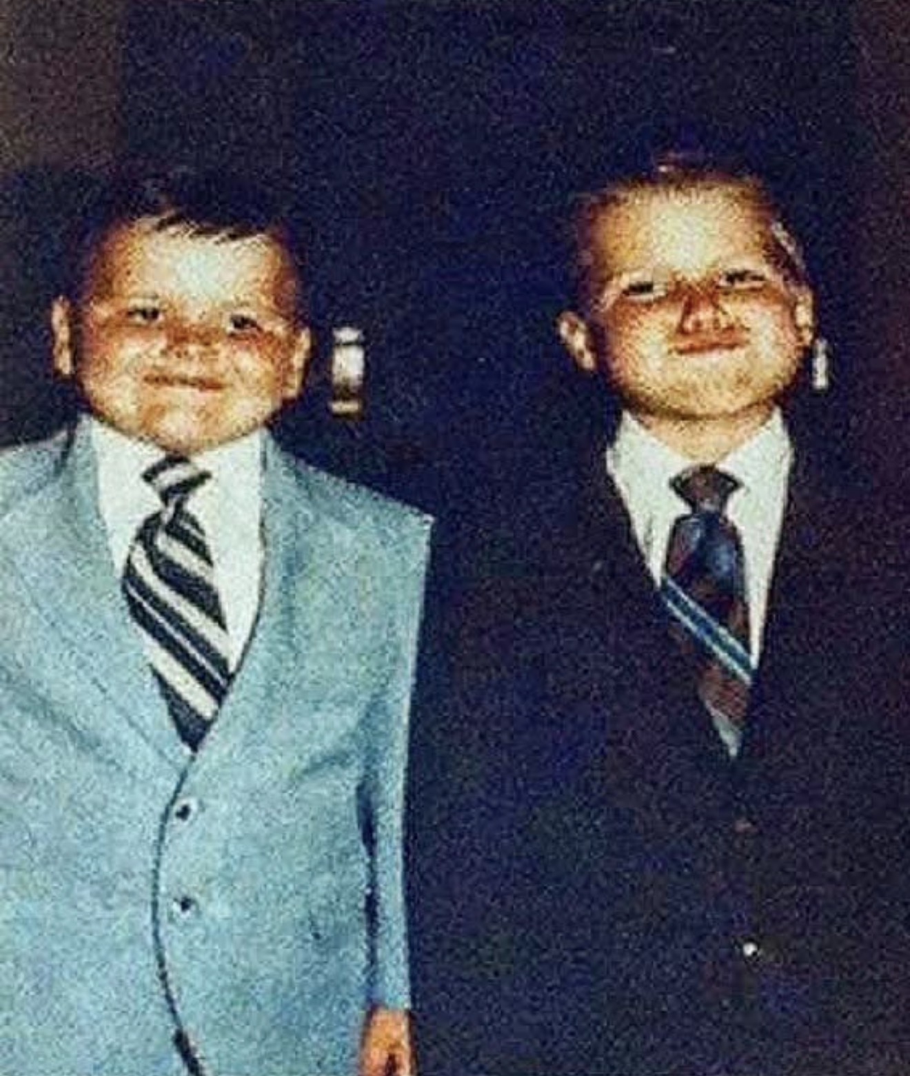 Two boys in suits and striped ties, grinning
