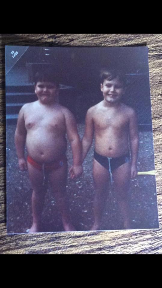 Two boys in swim trunks holding hands, a family snapshot from the archive