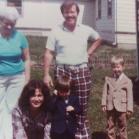 A family gathered in a backyard, boys in Sunday jackets