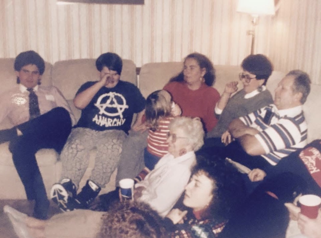 A big family crowded on a couch, one anarchy T-shirt among them