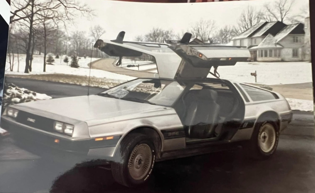 A DeLorean with gullwing doors open in the snow