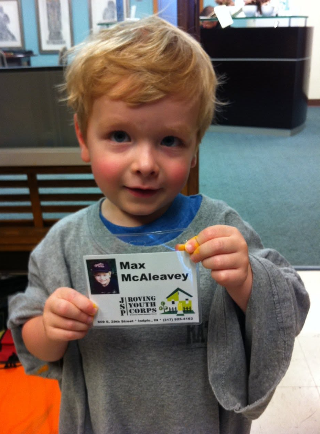 Young Max McAleavey holding his Roving Youth Corps badge.