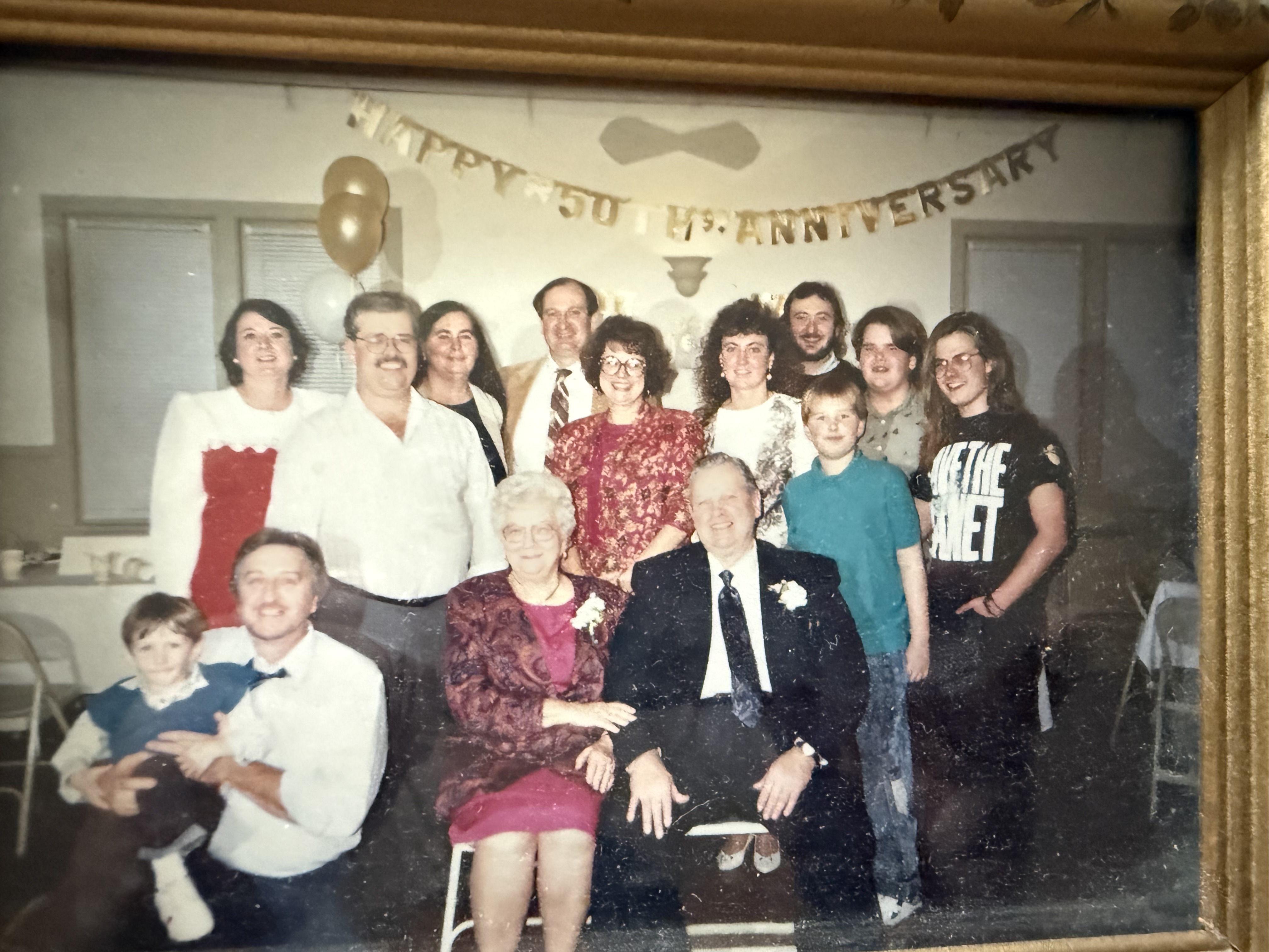 A framed photo of a large family at a 50th anniversary party
