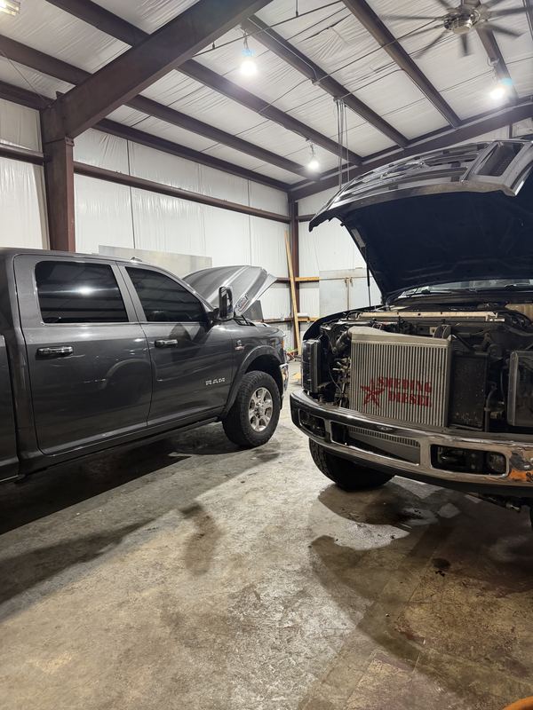 Ram and Ford diesel trucks in the EDP shop bay with hoods up