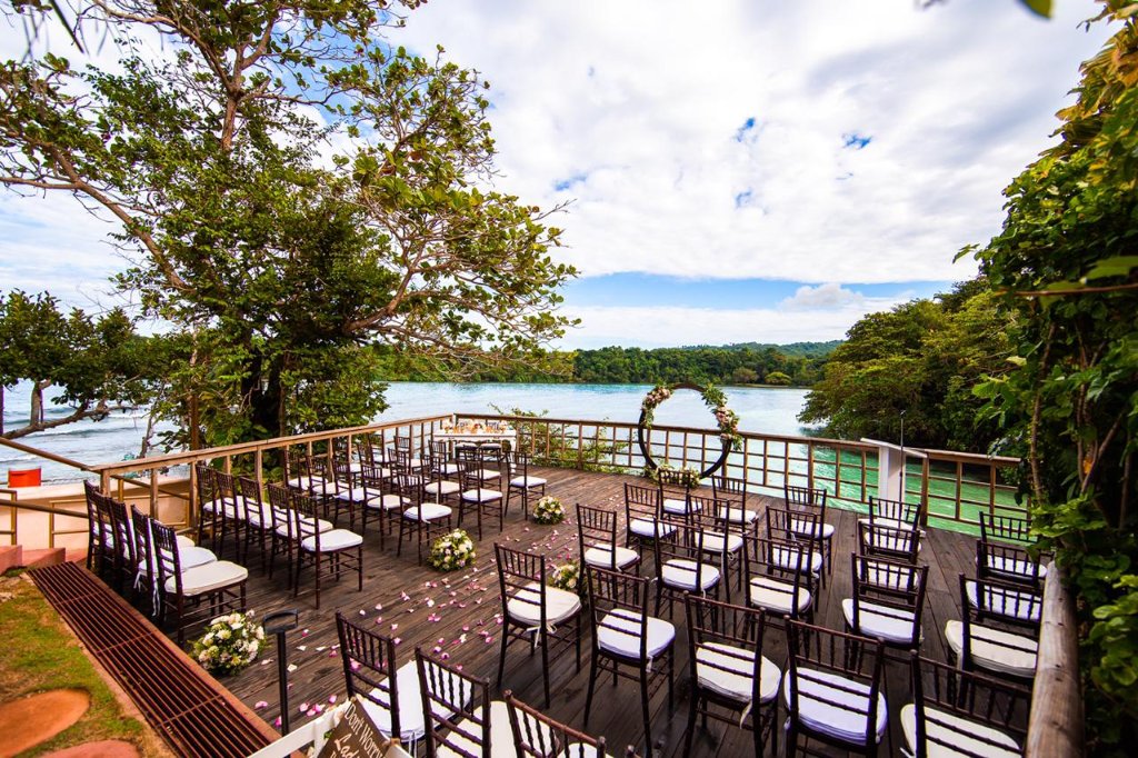 Wide elevated shot of full overwater ceremony deck with circular arch and San San Bay behind