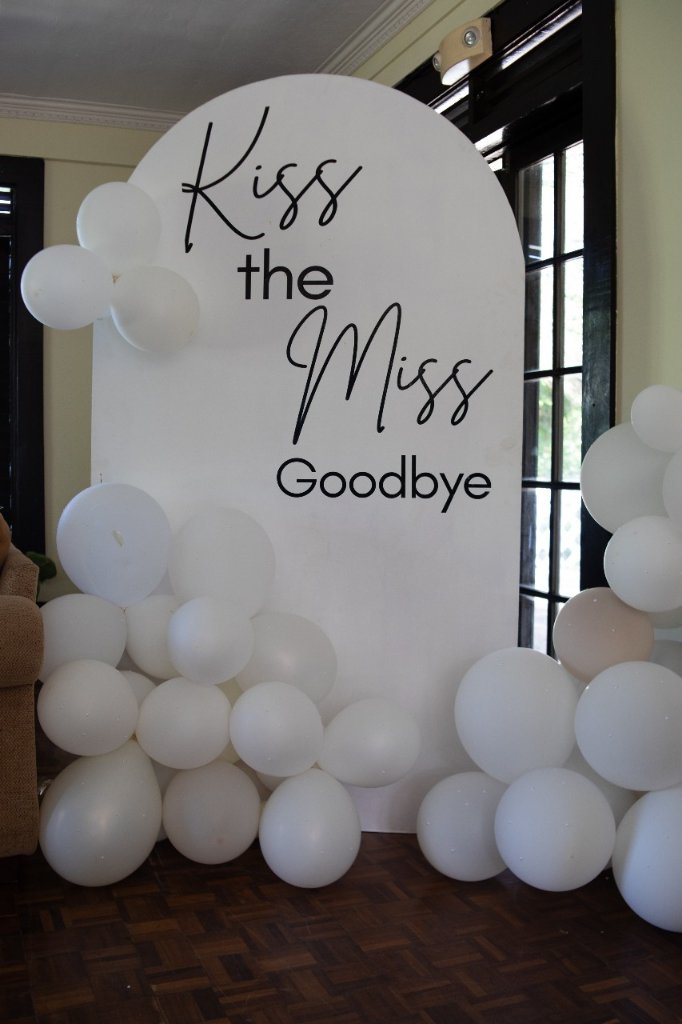 "Kiss the Miss Goodbye" white arch balloon backdrop at bridal suite