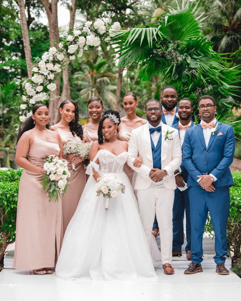 Couple and full wedding party formal portrait under floral arch