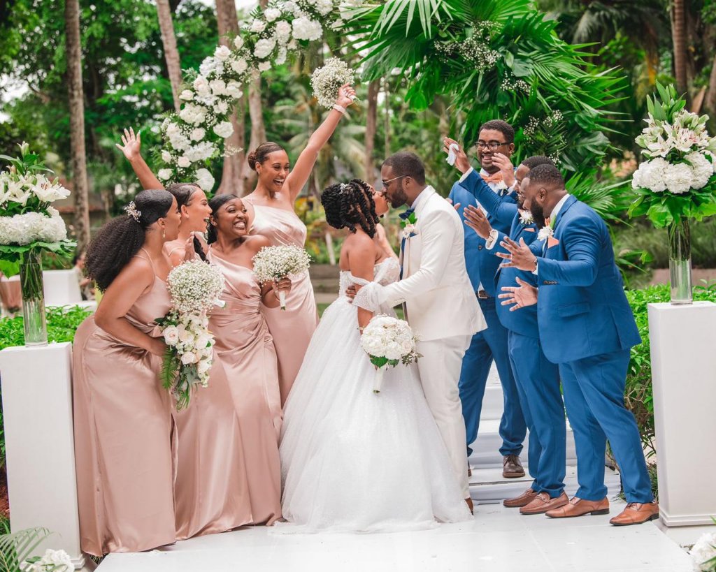 Wedding party erupting in cheers as couple kisses at the altar