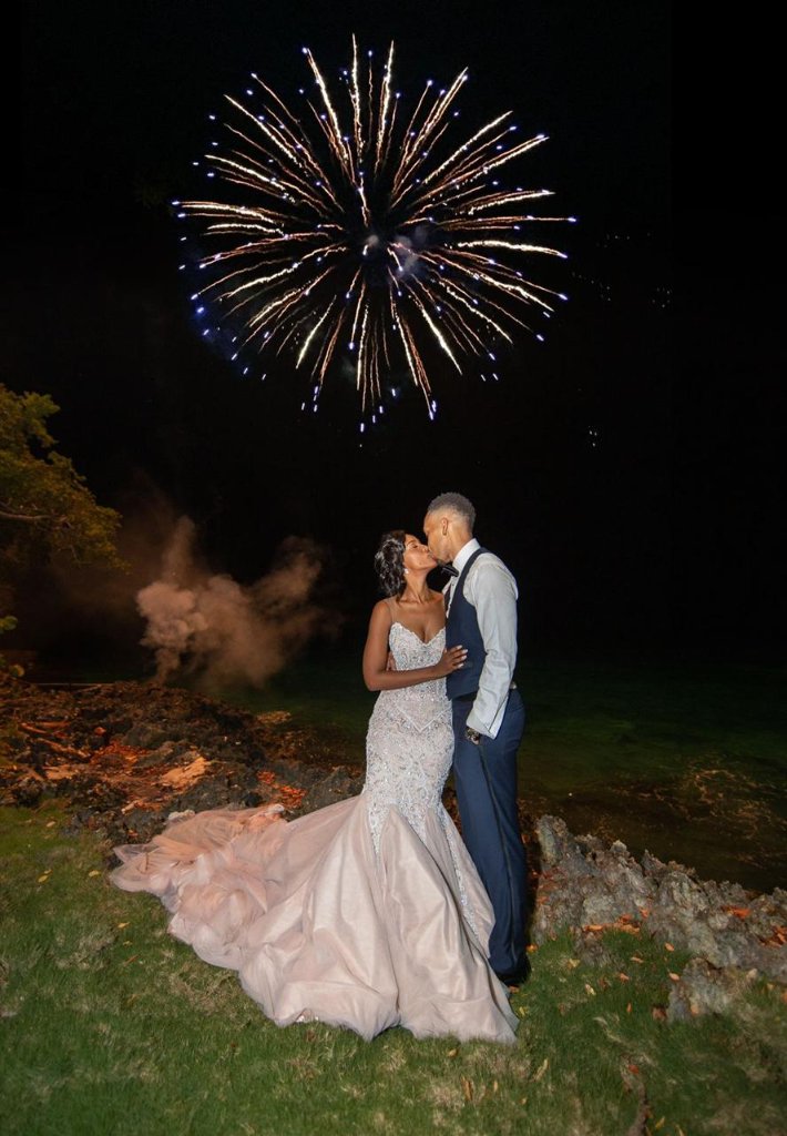 Couple kissing at night under a burst of fireworks with coloured smoke swirling around them