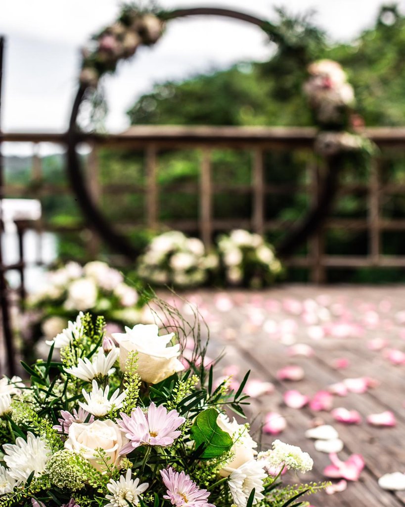 Close-up of white and lavender floral cluster with circular arch and petal-scattered deck softly blurred behind
