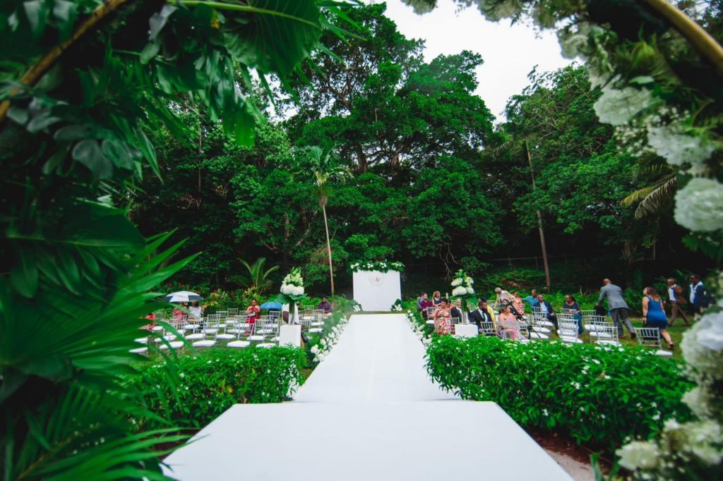 White floral moon arch with tropical greenery and lily pedestals