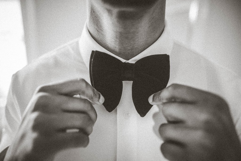 Groom adjusting black bow tie getting ready