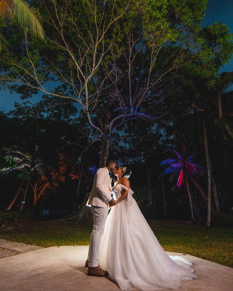 Couple dancing under lit trees at night reception