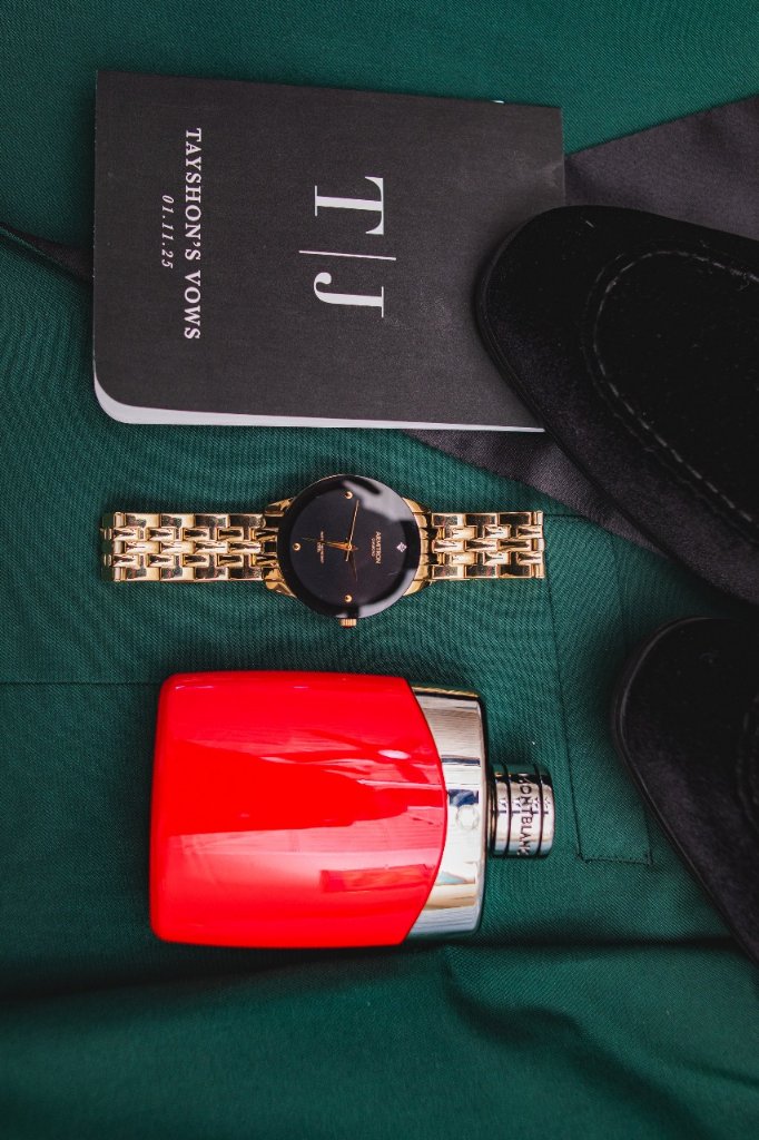 Groom's flat lay — T|J vows booklet, gold watch, Montblanc cologne and velvet shoes on emerald jacket