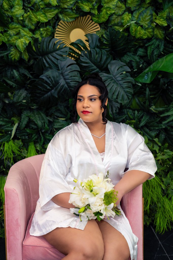 White Christian Louboutin bridal heels, MRS pearl clutch bag, passport holder and wedding invitation suite against green foliage backdrop