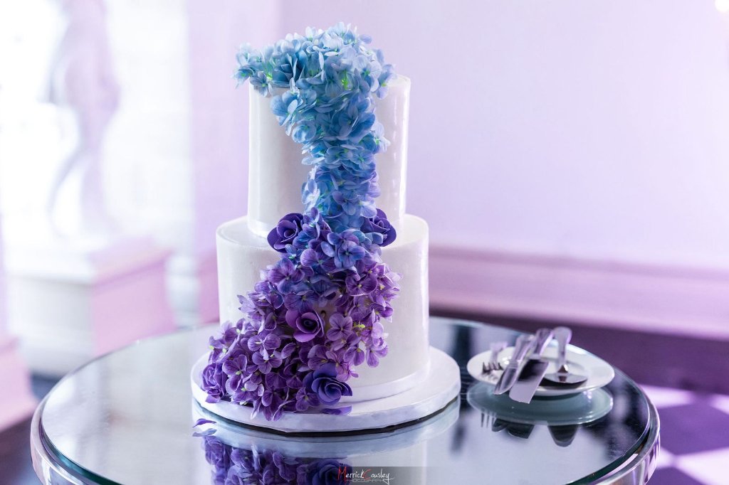 Stunning two-tier white wedding cake with cascading blue to purple hydrangea florals