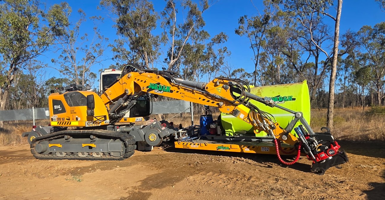 Hi-rail excavator with spray tank unit on rail trailer