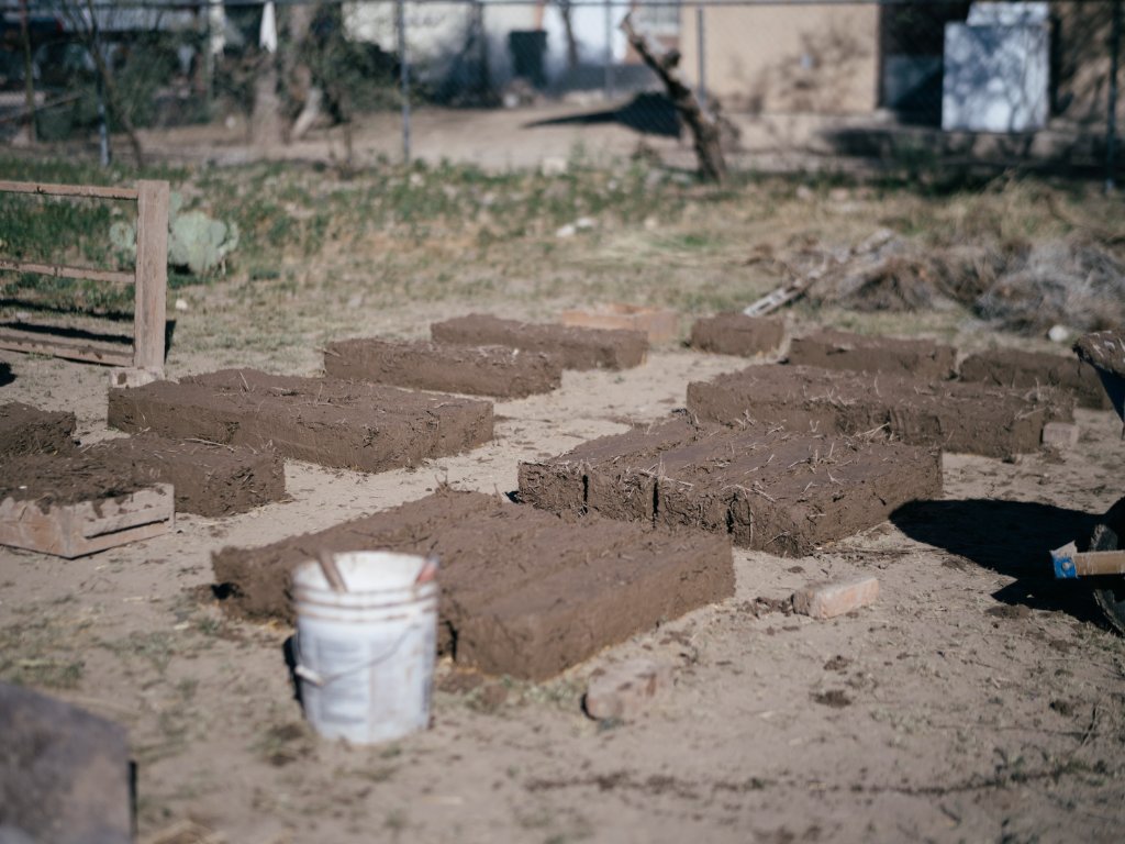 Fresh adobe buffelgrass bricks laid out in the desert sun to cure