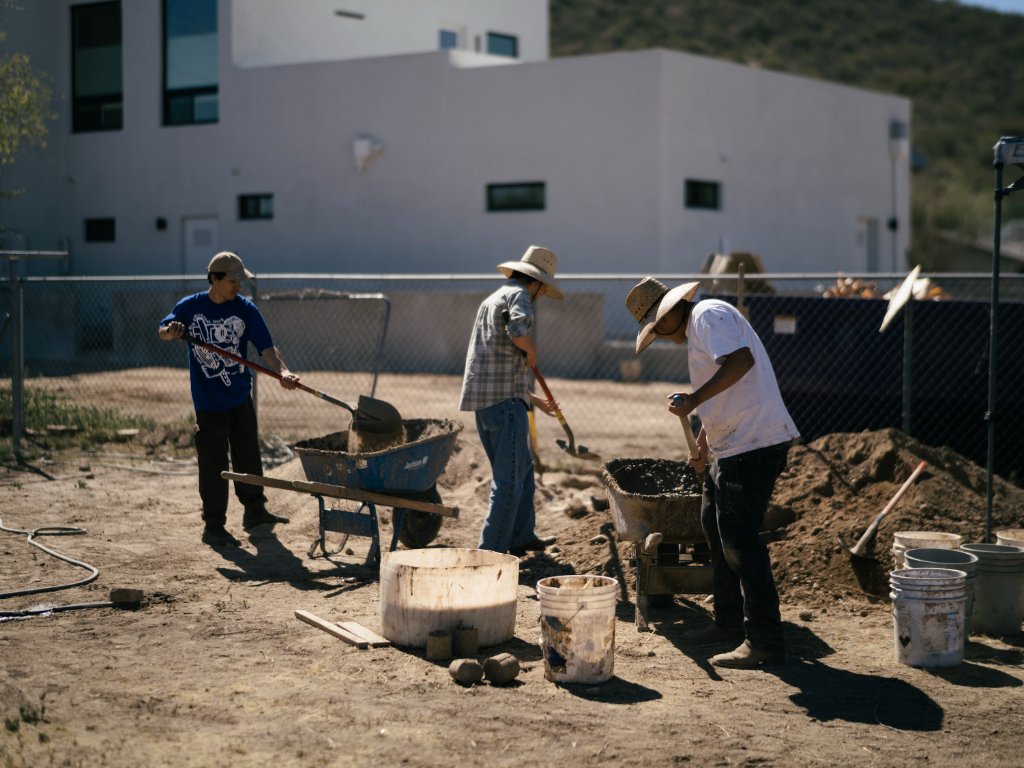 Volunteers shoveling dirt and sand into wheelbarrows at the brickyard