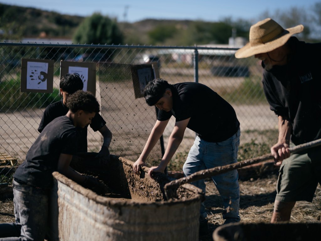 Volunteers working clay slip into buffelgrass at the brickyard
