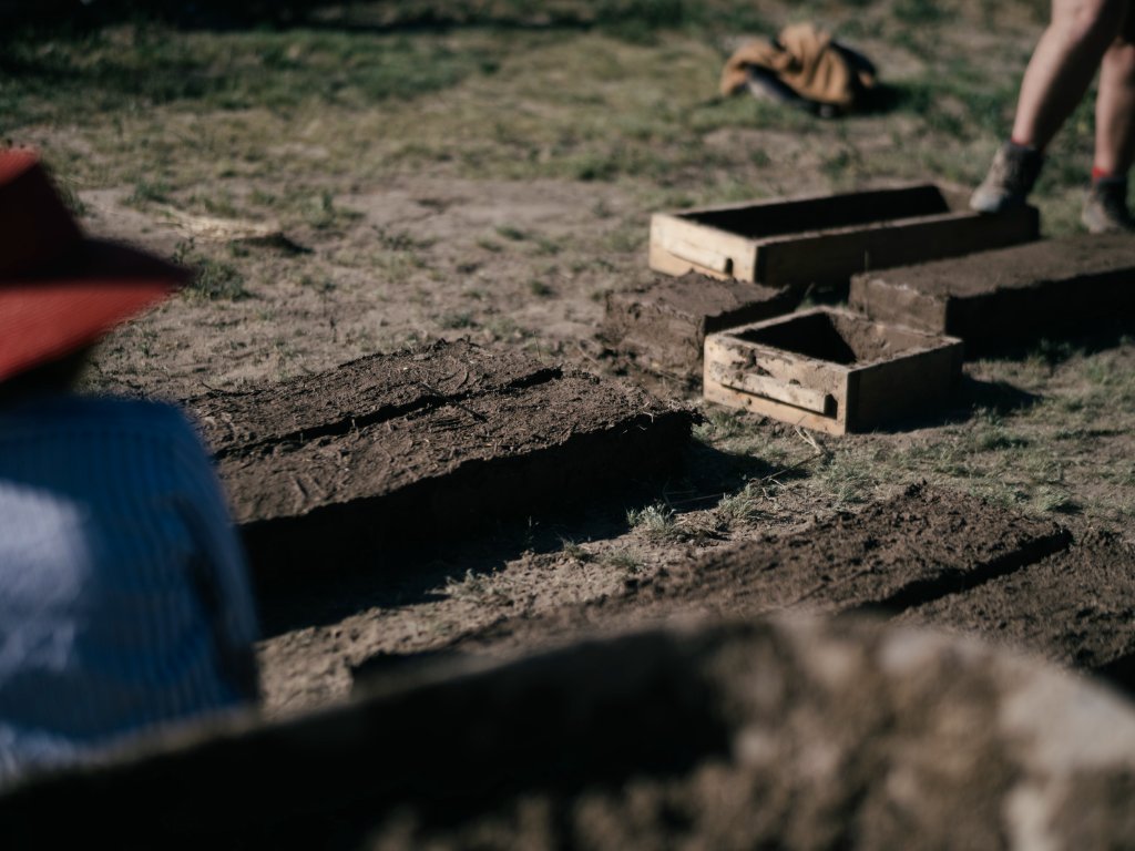 Brick forms at various stages with wooden molds removed, showing cured adobe bricks