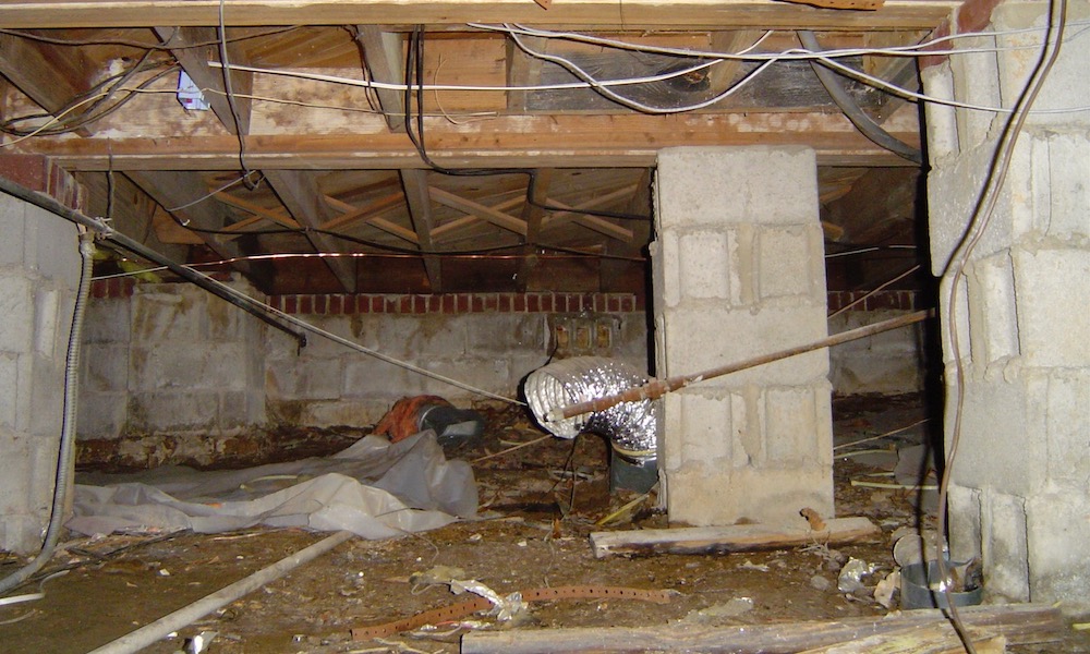 Before: crawl space with damp soil and failing insulation