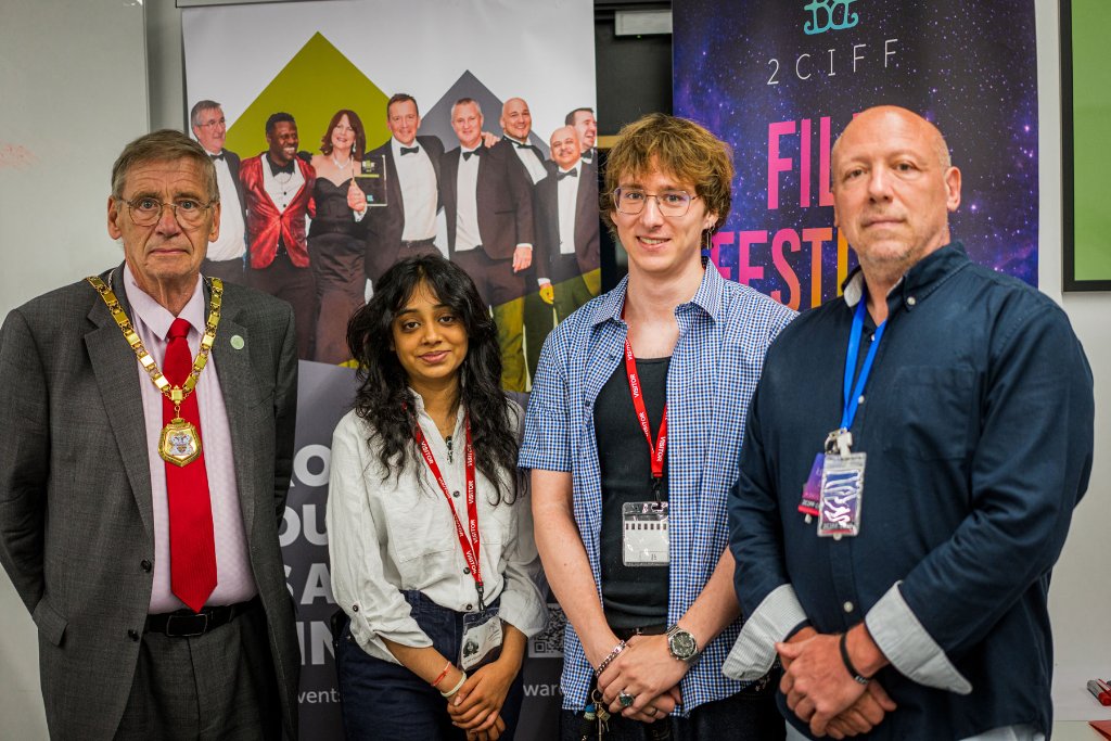 Four attendees posing together with event banners in the background