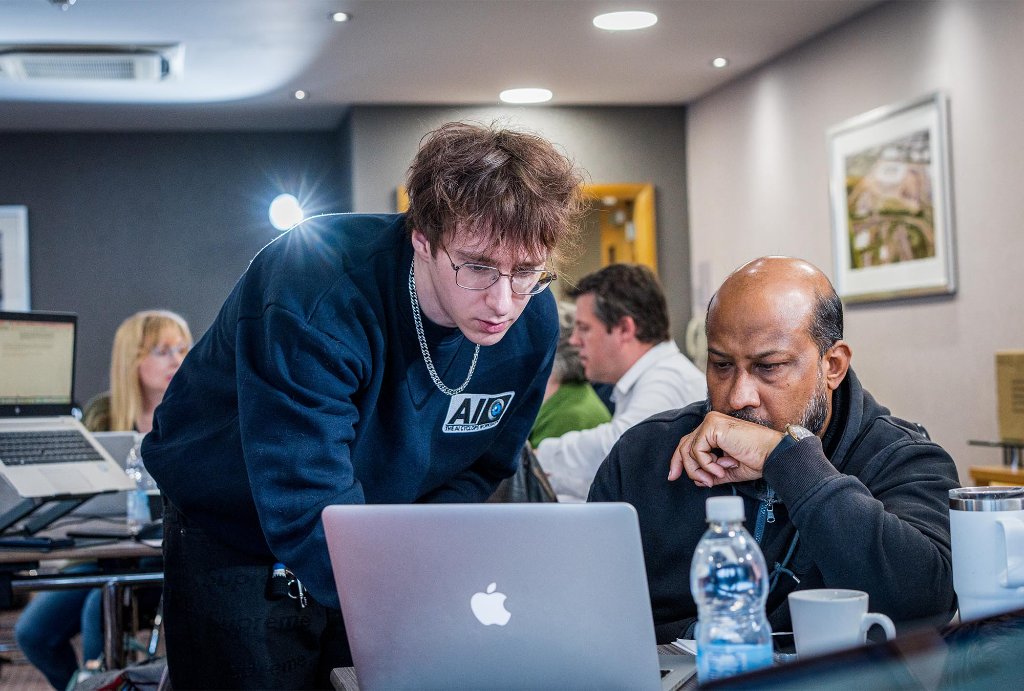 Two attendees helping each other at laptop