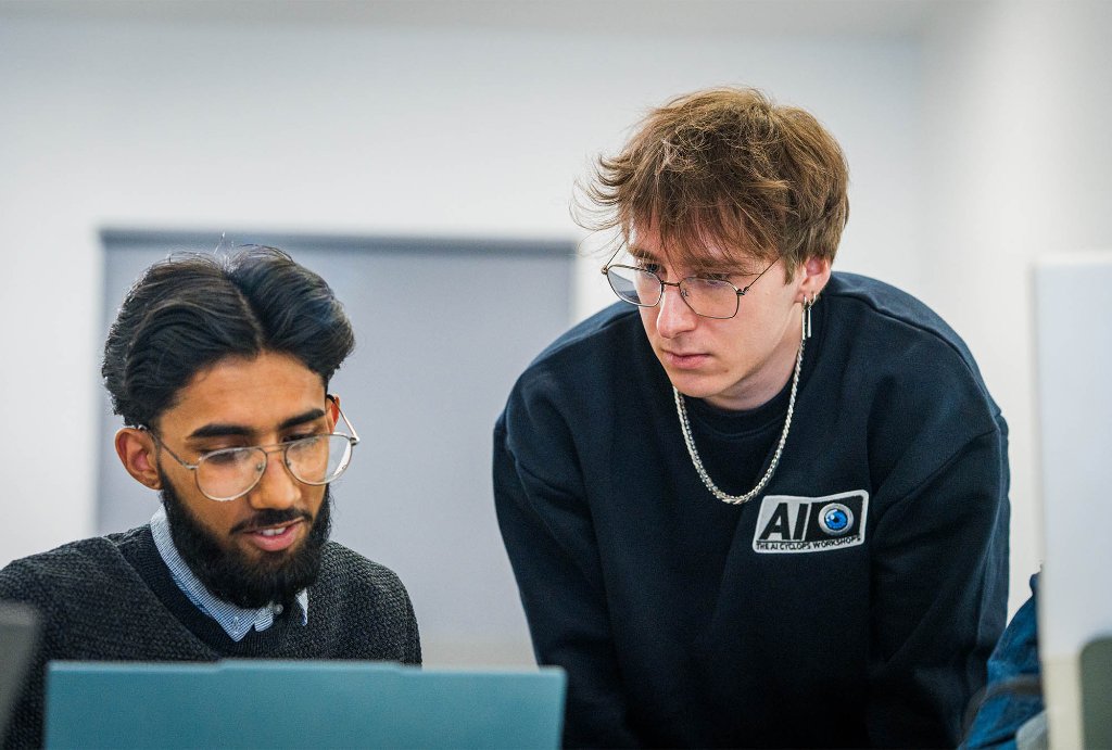 Trainer helping student at laptop