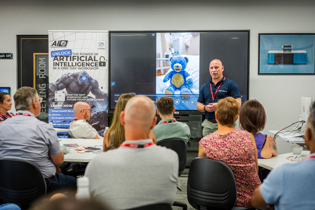 A presenter demonstrating AI tools on a large screen to the seated audience