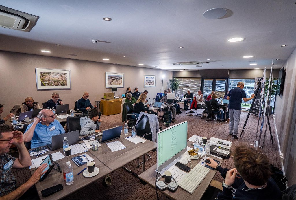 Wide view of workshop room with all attendees engaged on laptops