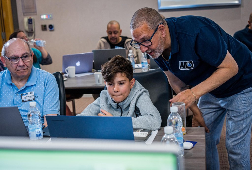 Young team member coaching older attendee at tablet