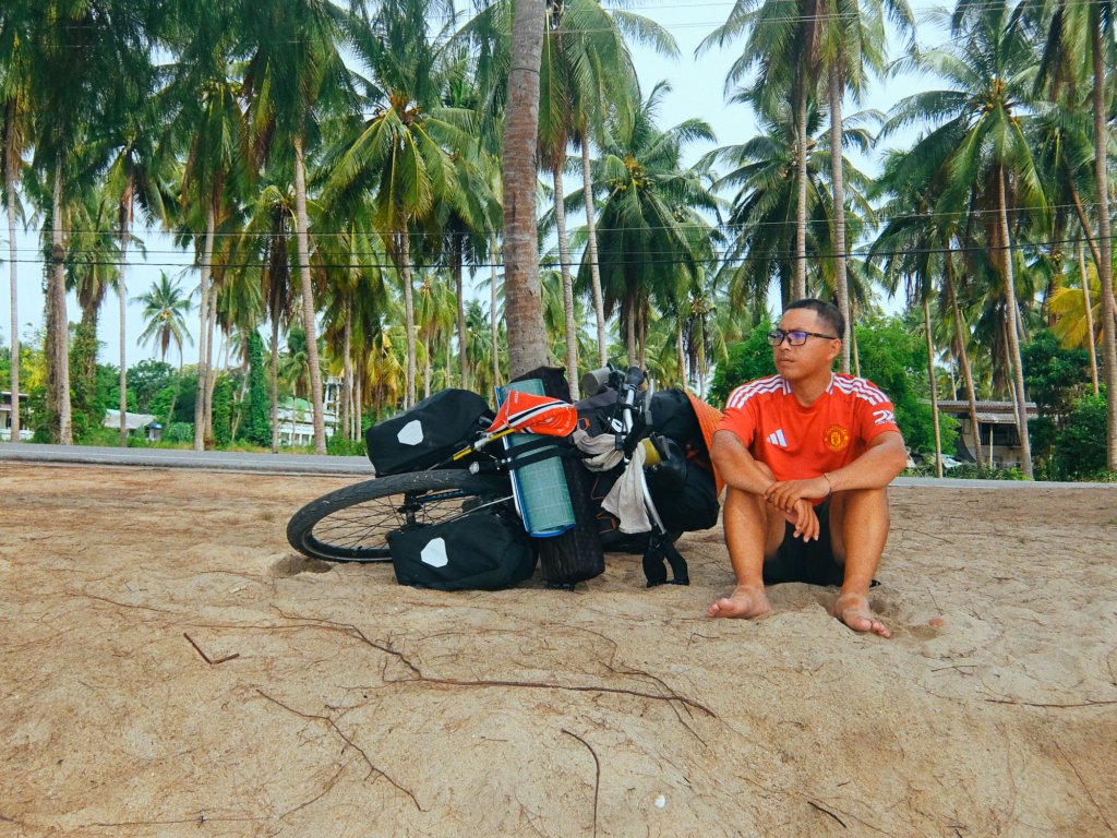 Gom resting beside his bicycle on the road