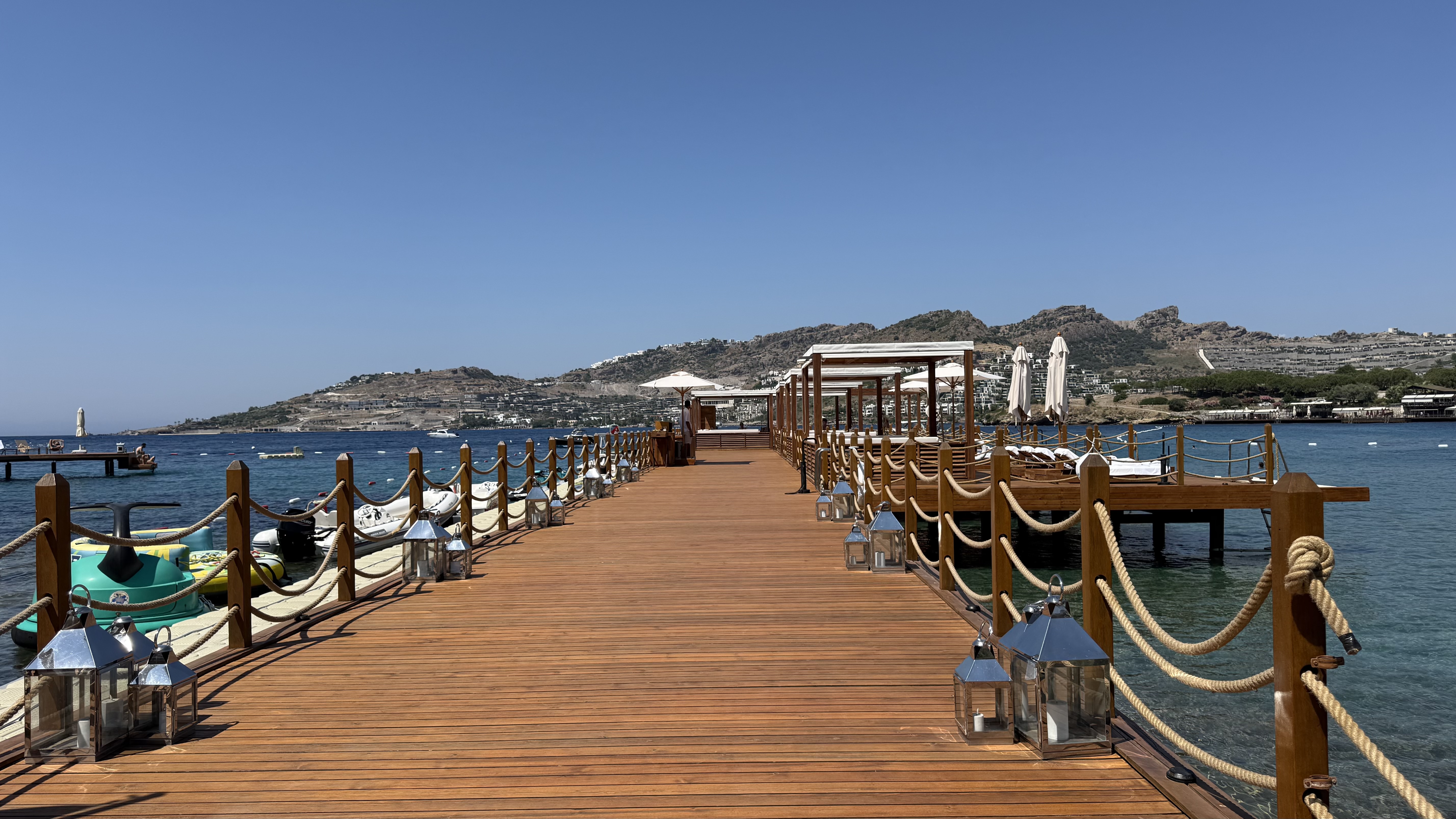 The pier — teak boardwalk with rope lanterns stretching into the bay