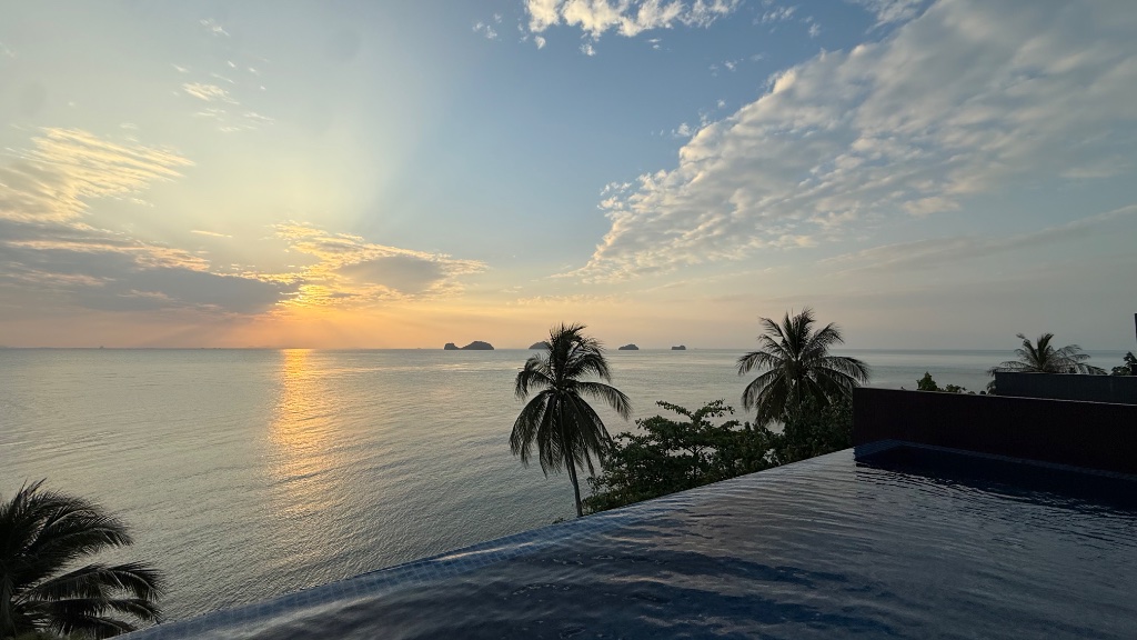 Sunset from the main pool — the sun drops behind the Five Islands in a wash of gold