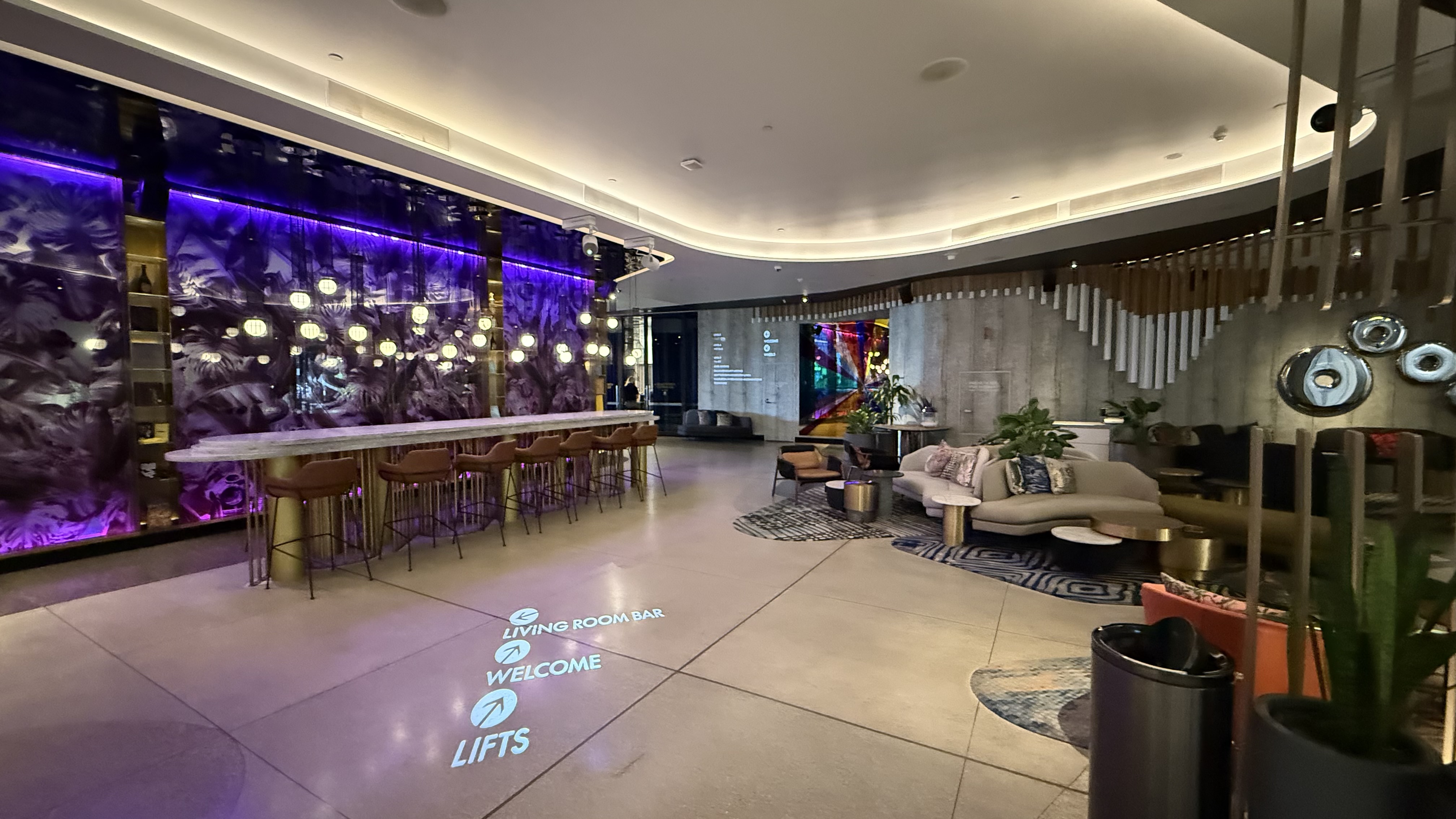 The lobby at night — the Living Room Bar, directional floor lighting and lift signage