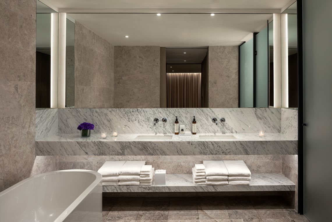 Loft bathroom — double marble vanity, Le Labo products and backlit mirror