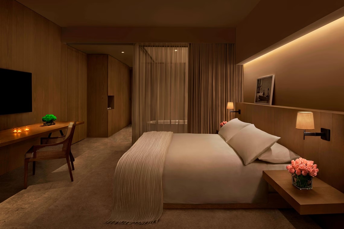 Deluxe Garden View Room — warm oak panelling, cane-back desk chair and sheer bathroom partition